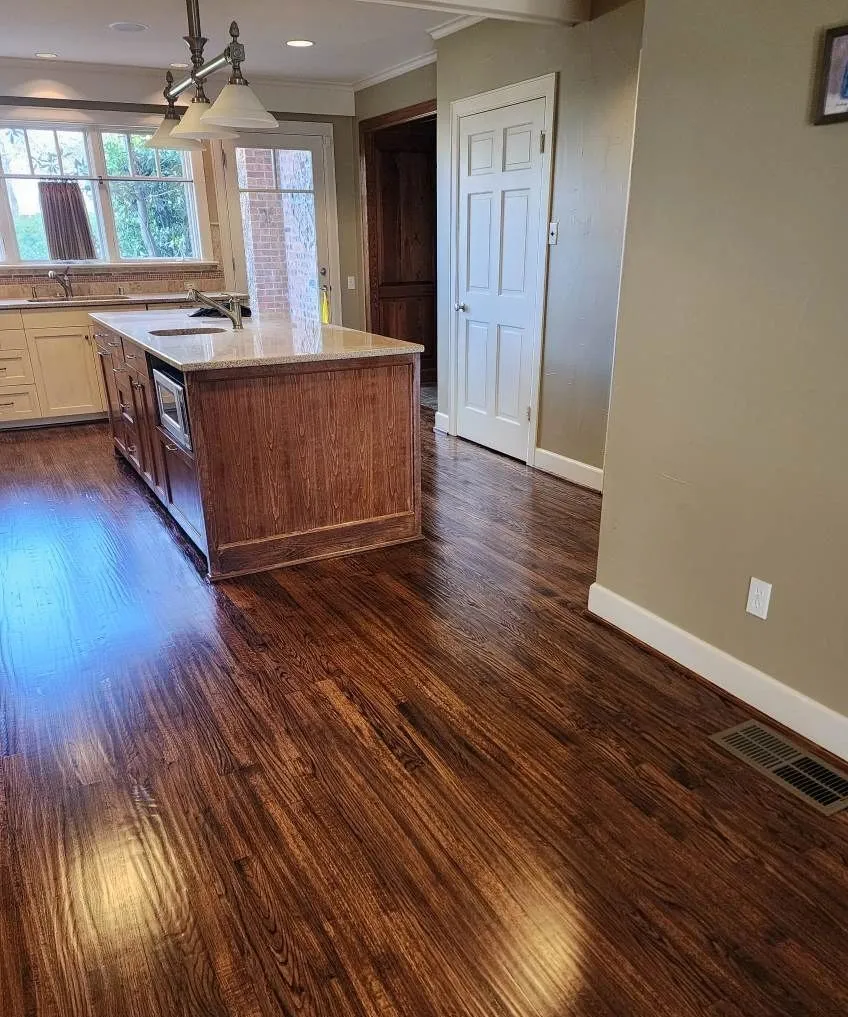 Dark stained hardwood flooring running through a kitchen with a wood island in a McKinney TX home